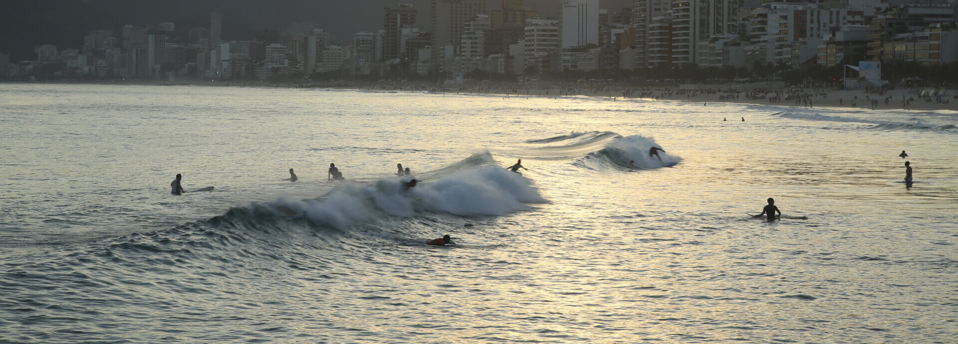 People surfing in the ocean with a city skyline behind
