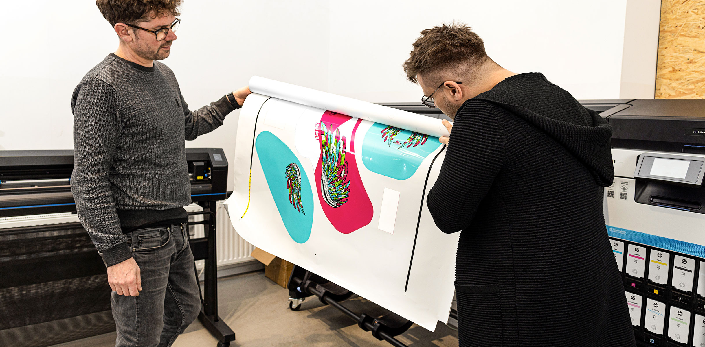 People checking printed media in fron of HP Latex Print and Cut Plus solutions