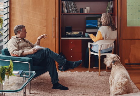 People in a family room setting with a laptop on a desk