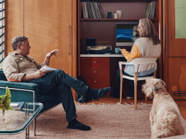 People in a family room setting with a laptop on a desk