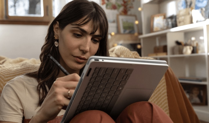 A person sitting at a table in a café using their HP OmniBook 5 laptop
