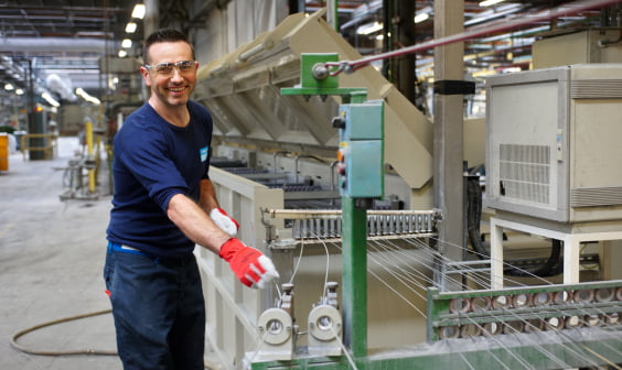 smiling man in manufacturing center, with gloves and safety glasses