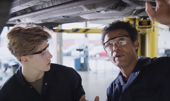 young male student and professional man in safety glasses at a manufacturing center