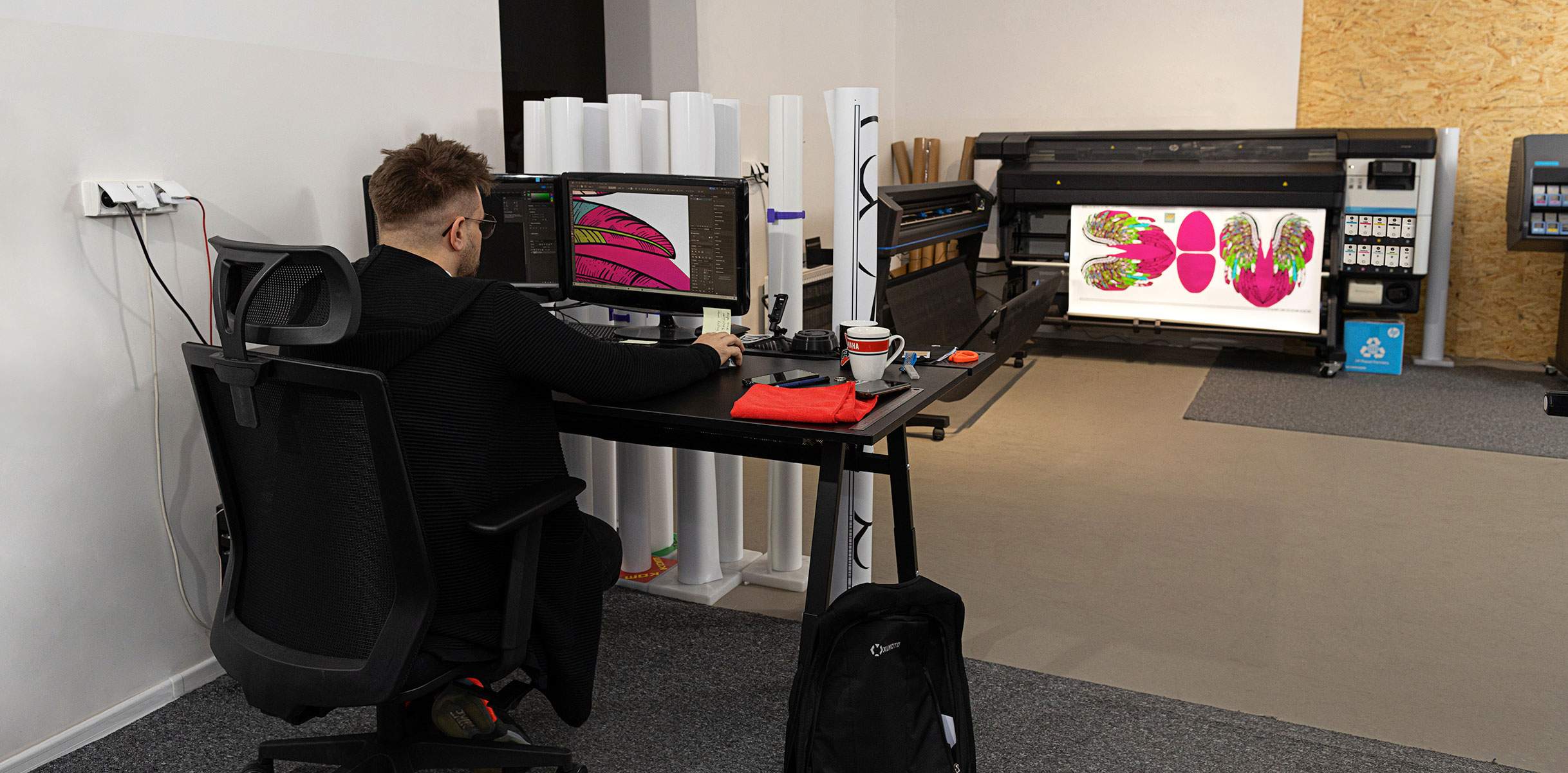 Person working in a computer in front of HP Latex Print and Cut Plus solutions