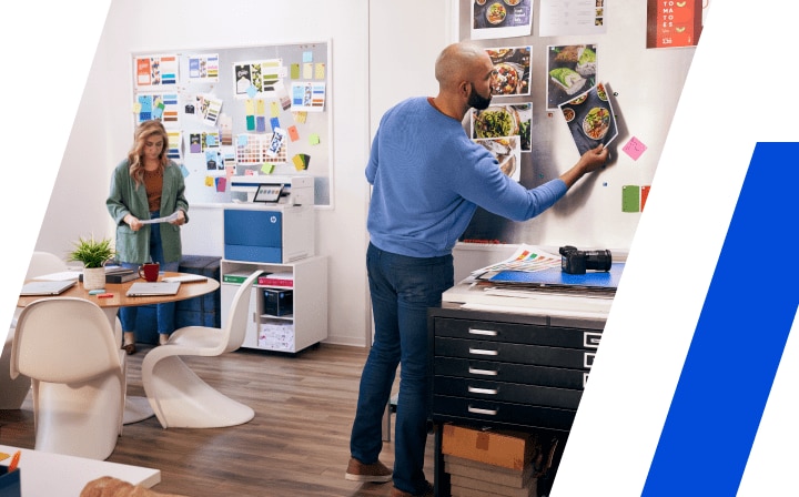 Person pinning photo prints on an office bulletin board