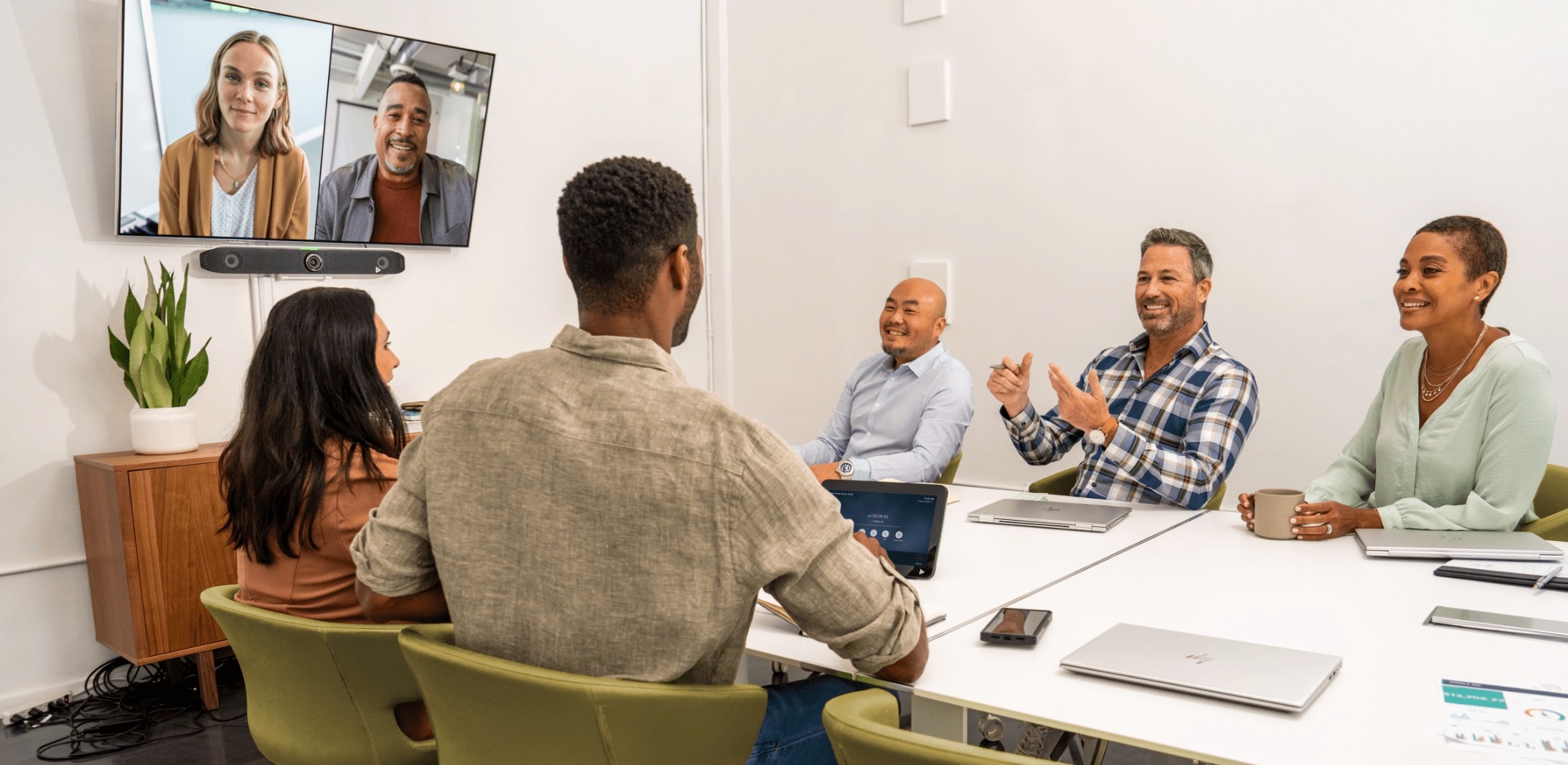Group of people in a medium-sized conference room, engaged in a video call using the Poly Studio X52 all-in-one video bar