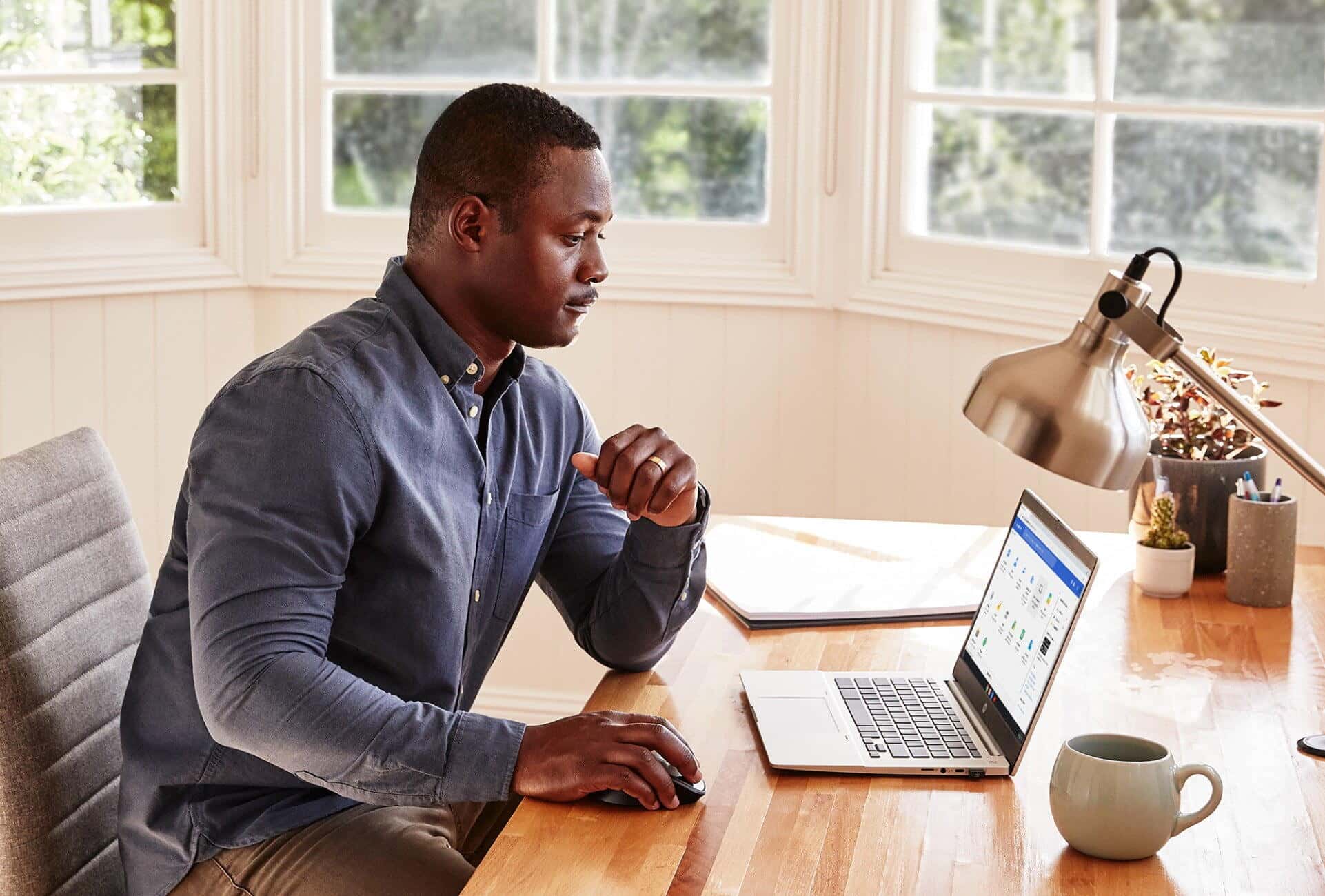 A man working on an HP laptop in his home office desk