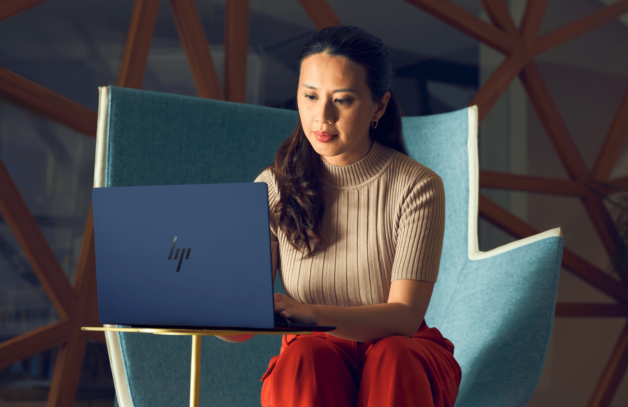 Woman working on an HP laptop aside a cup of coffee