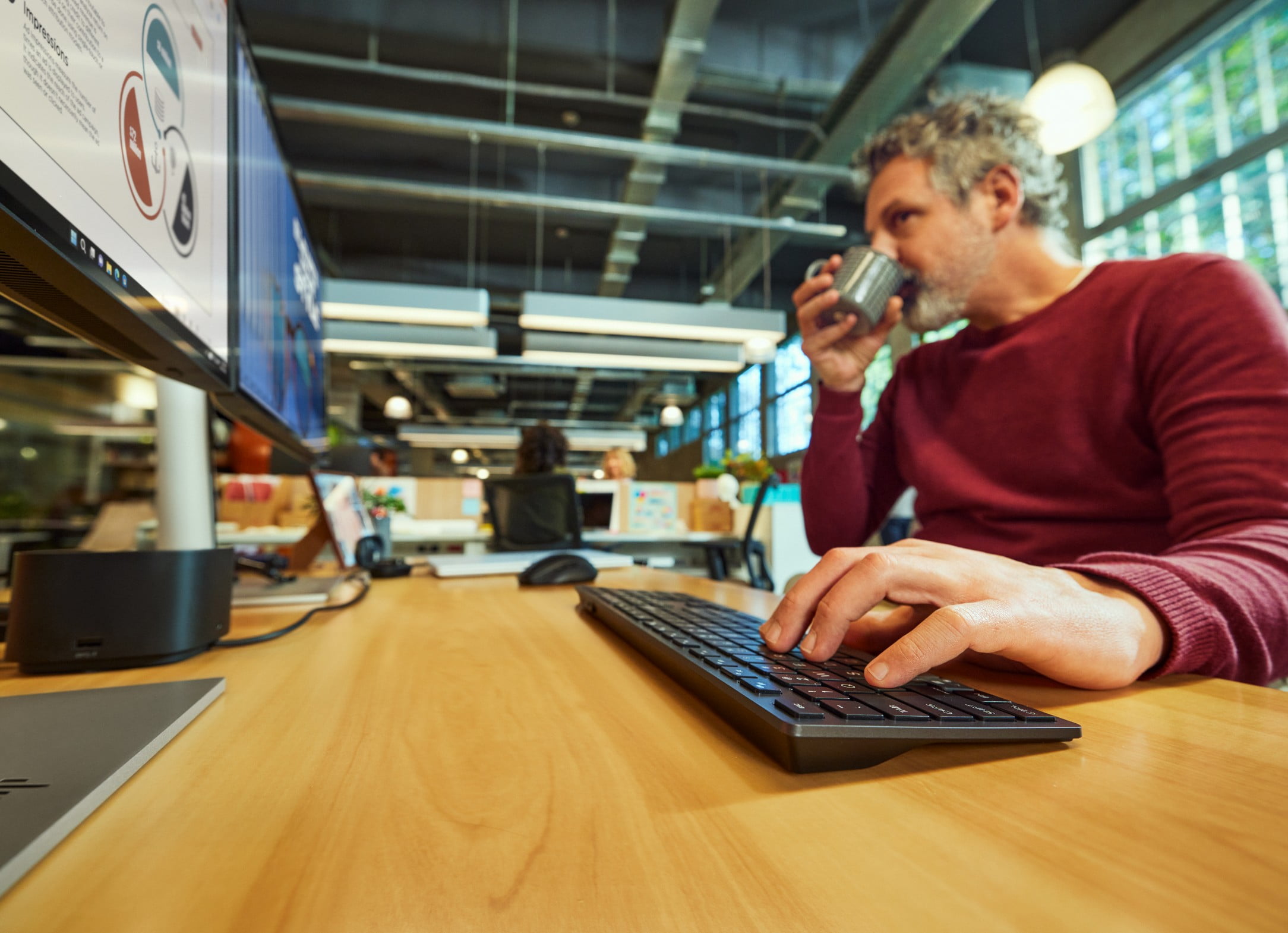 A man working on HP dual monitors with an HP wireless keyboard and mouse.