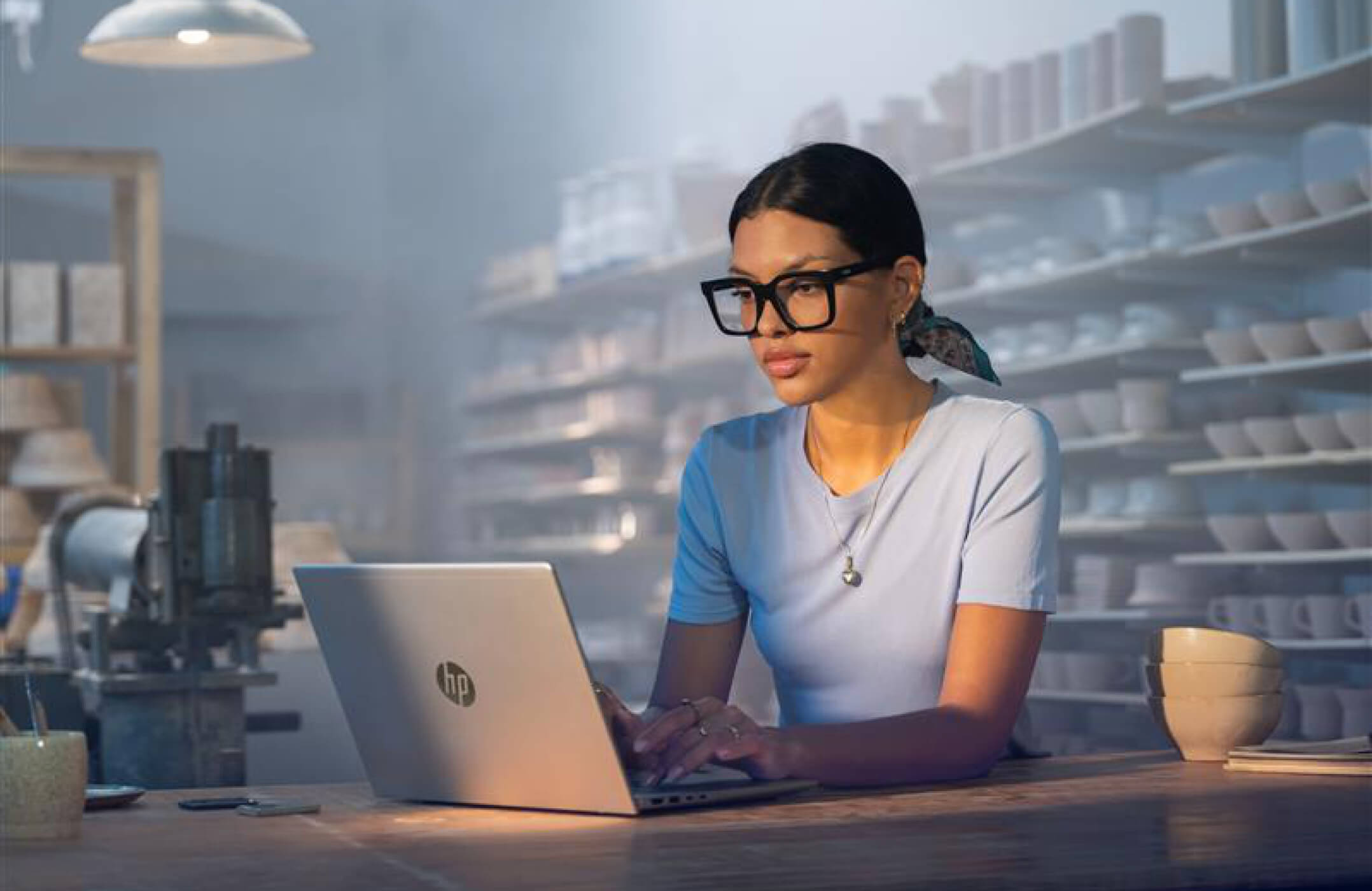 A woman wearing glasses working on an HP ProBook laptop