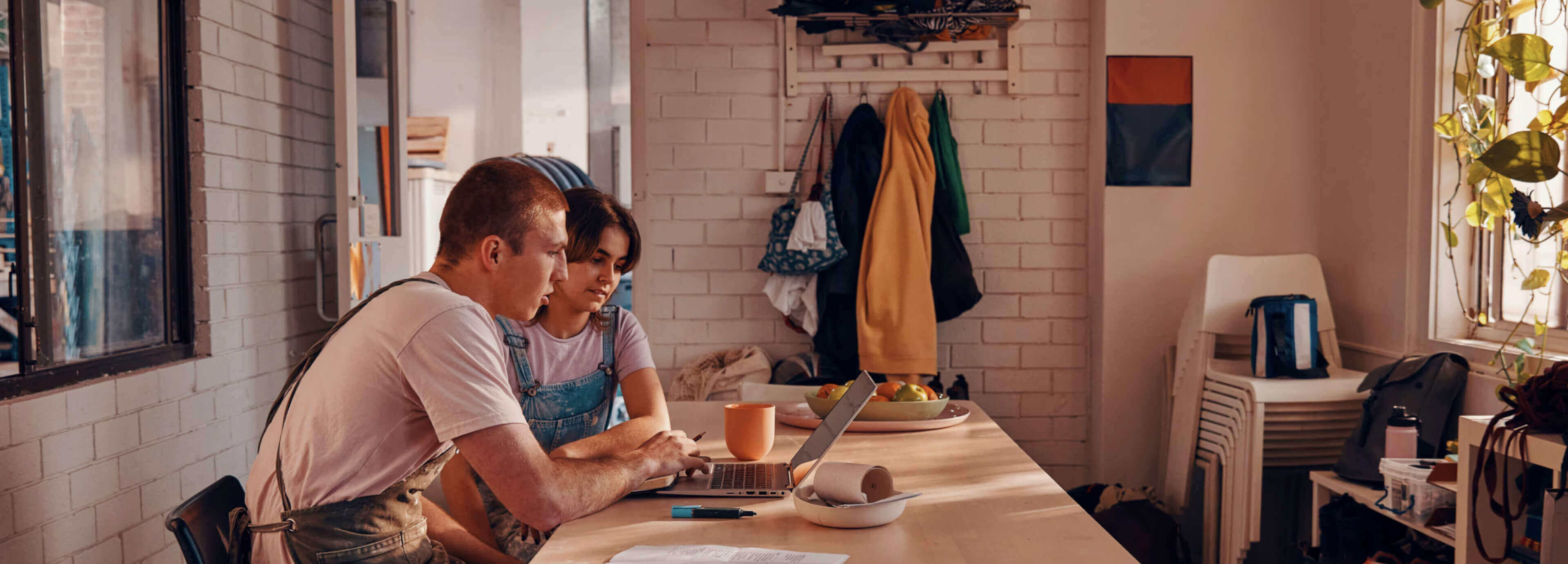 A man and woman working together at a counter on an HP laptop