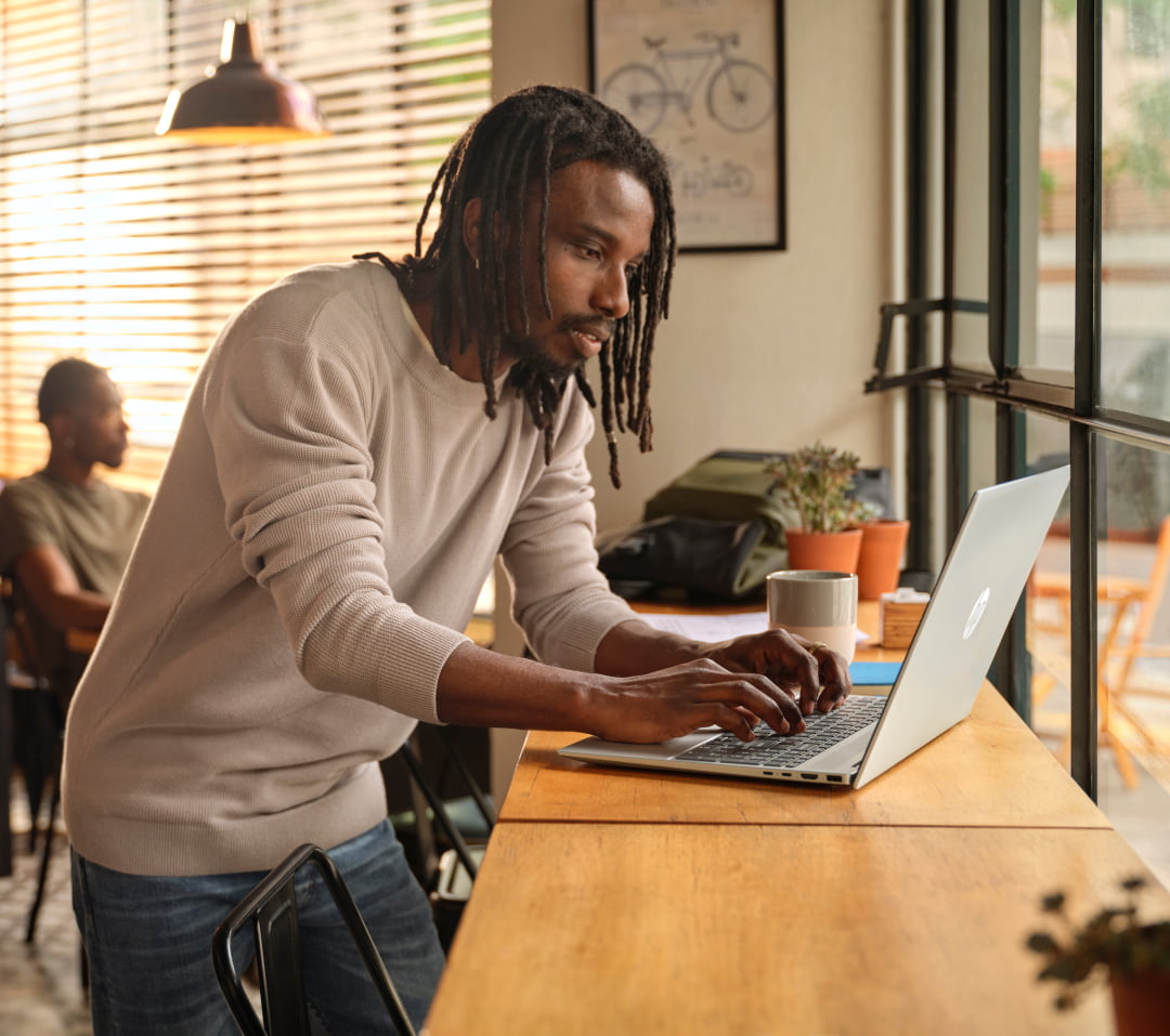 male professional in coffee shop using HP laptop for remote work