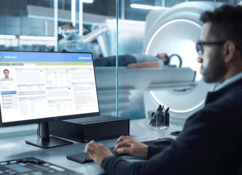 A radiologist sits at a computer monitor connected to an HP desktop PC to fill data as part of a patient's examination.