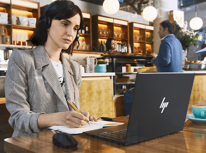 professional woman in coffee shop using HP Poly headset and HP laptop