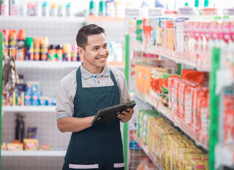 Supermarket worker checking inventory in an HP Engage Go 10 system in tablet mode.