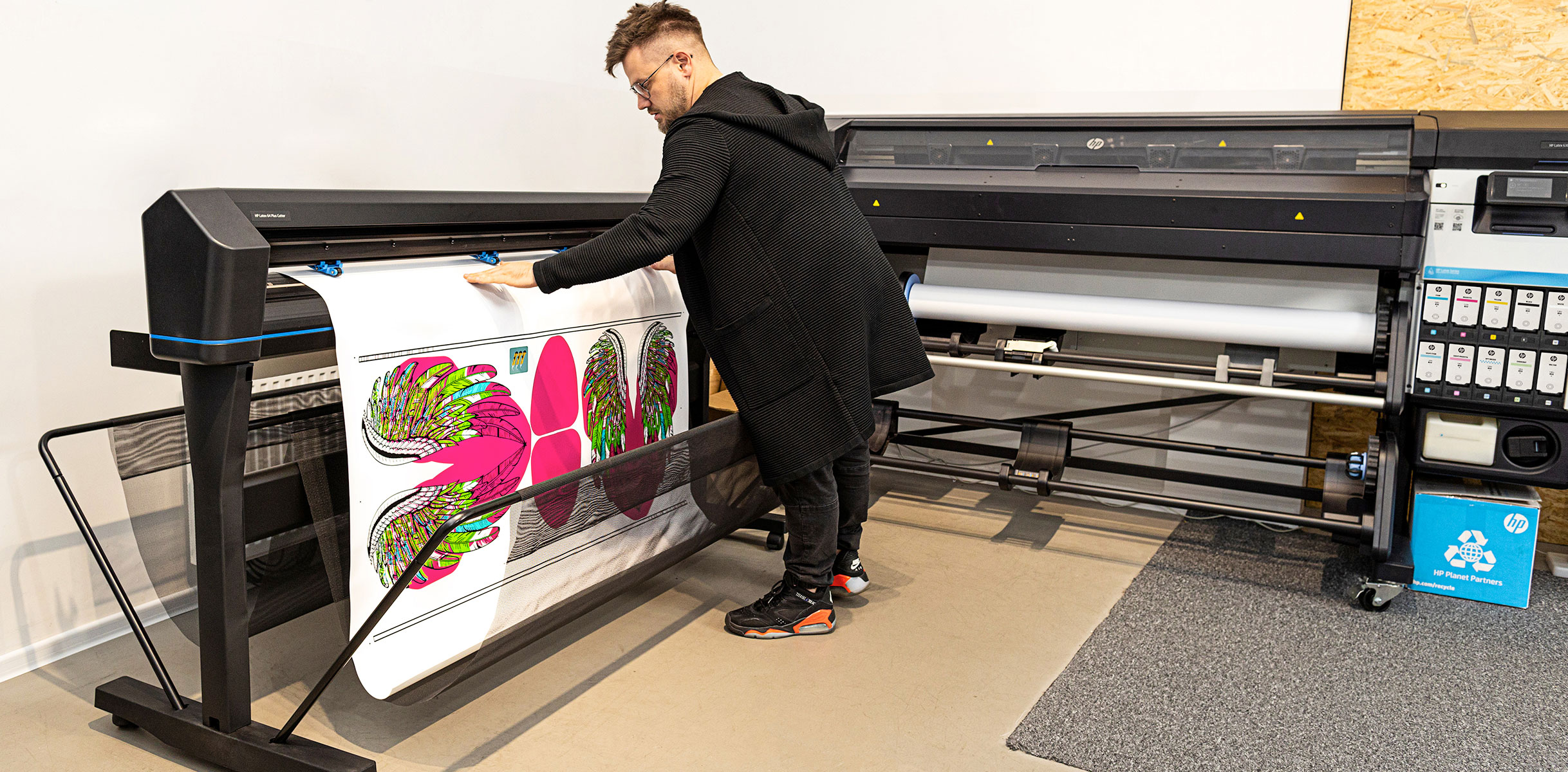 Person checking printed media coming out from an HP Latex Print and Cut Plus solution