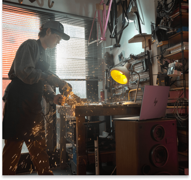 A man using an angle grinder aside an HP OmniBook in his workshop