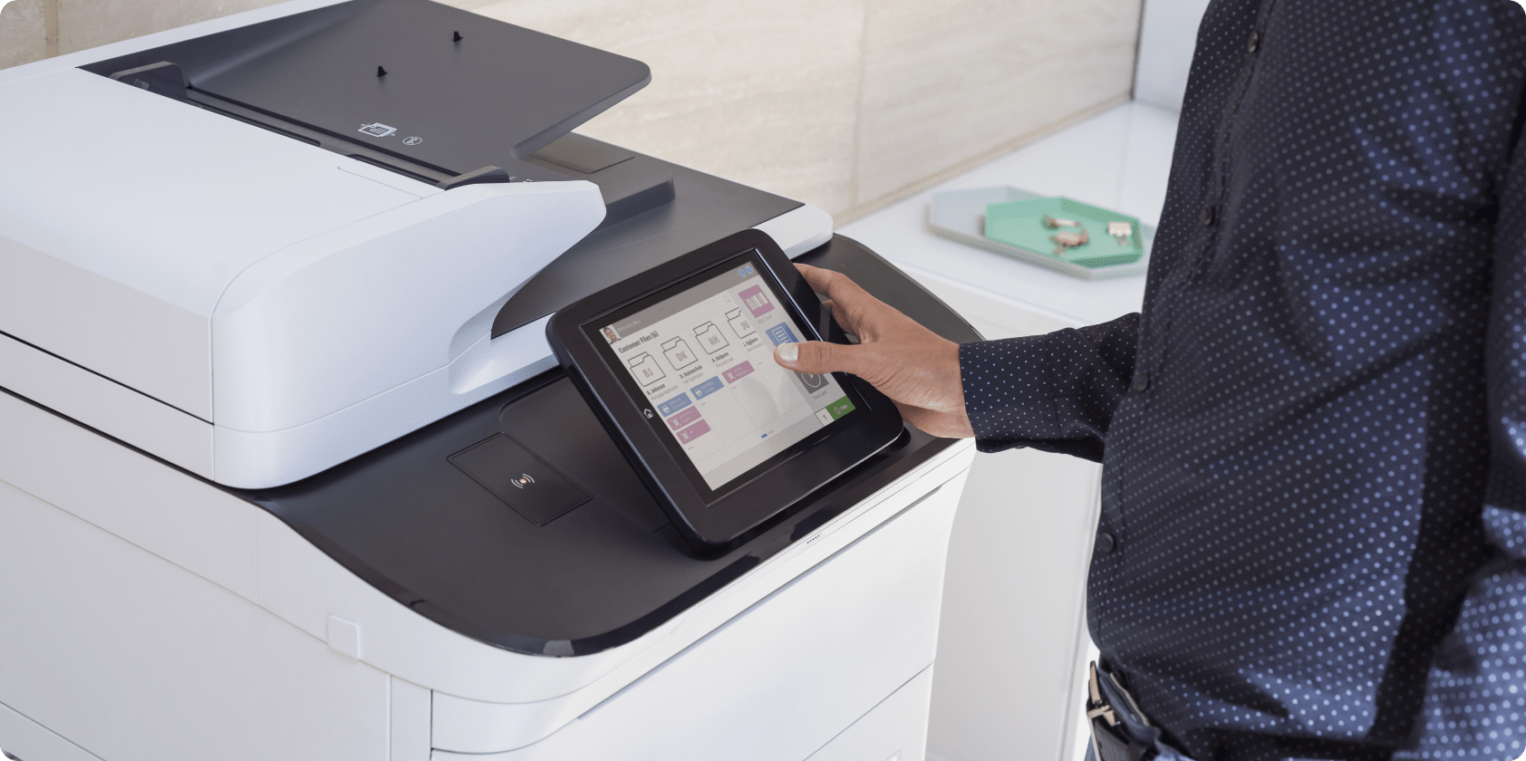 Close view of HP LaserJet Enterprise MFP touchscreen and employee's hand touching the controls