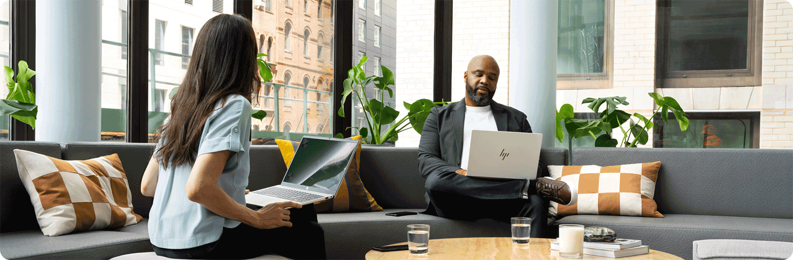 professional man and woman seated in an office lounge, using HP laptops